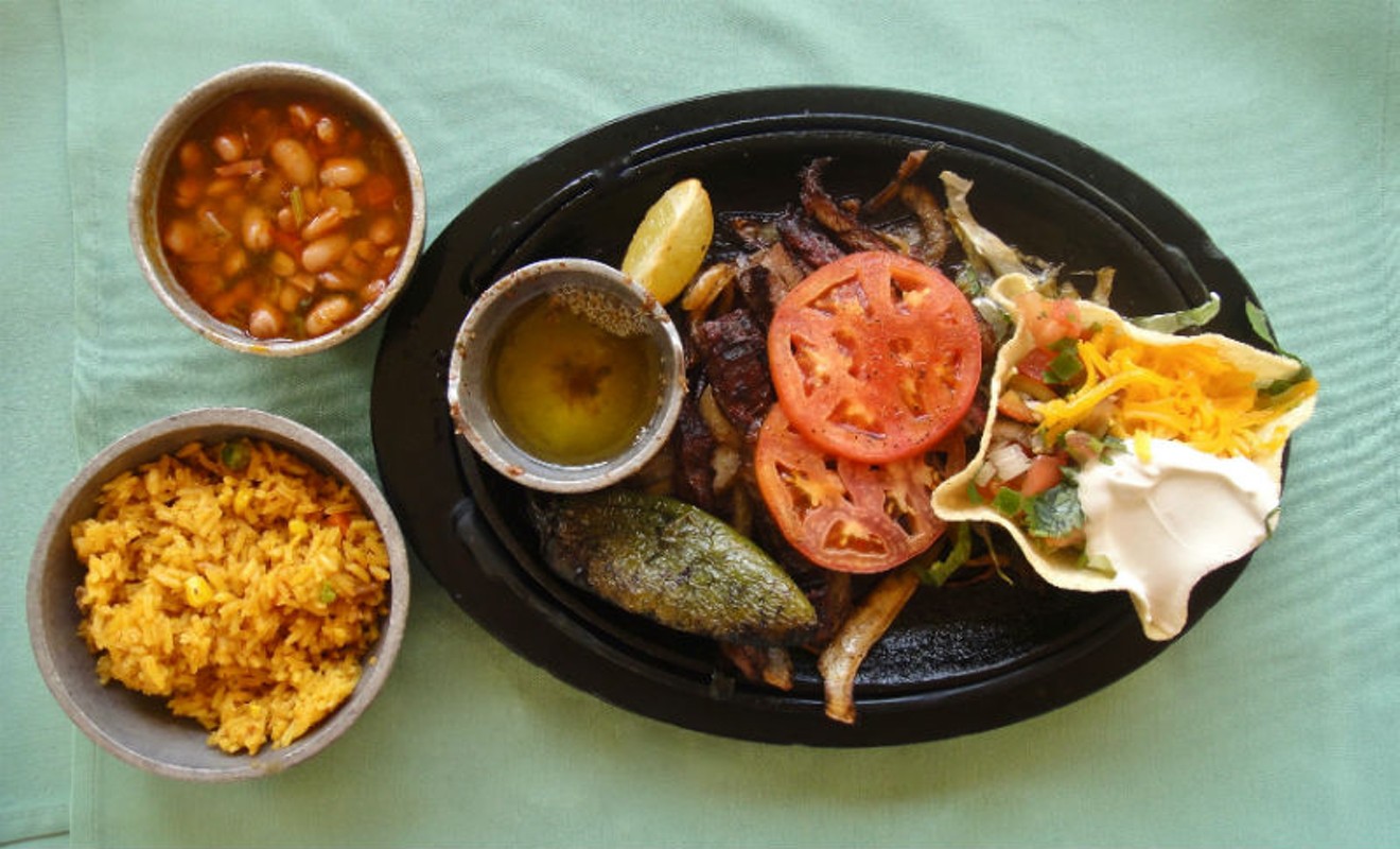Fajita platter at El Tiempo Cantina served with charro beans and rice, garnished with a chile toreado.