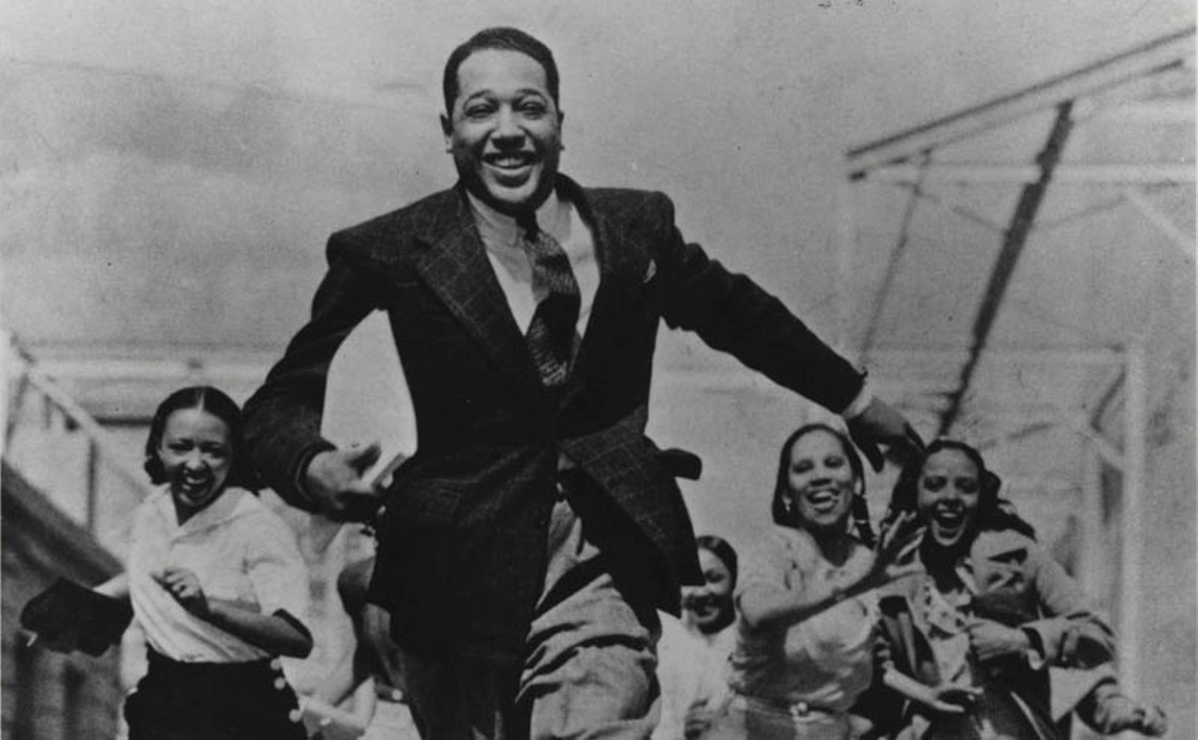 In a sure sign that this was a staged photo, elegant bandleader/pianist/songwriter Duke Ellington is running FROM avid female fans.