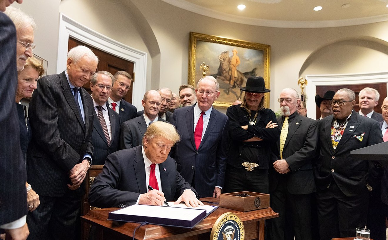 President Donald Trump signs the Music Moderizaiton Act on October 11, 2018. Performers inlcuding singer/rapper Kid Rock (wearing a hat, 'natch), former Steely Dan/Doobie Brothers guitarist Jeff "Skunk" Baxter, and soul legend Sam Moore of Sam and Dave look on.