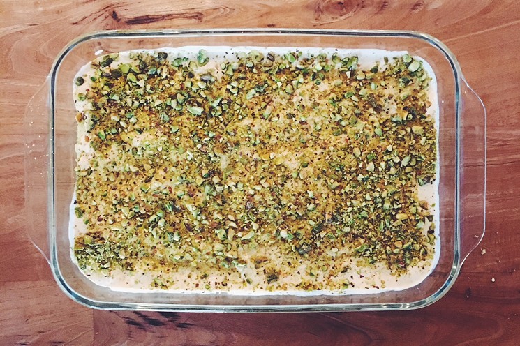 A large pan of liali lbnan (semolina pudding) topped with cream and chopped pistachios. - PHOTO BY ERIKA KWEE