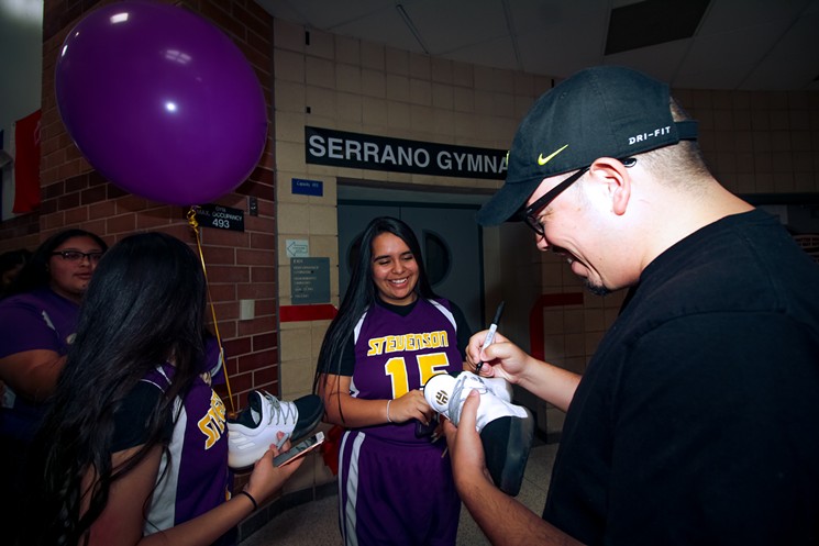 Steven "Shea" Serrano signs basketball shoes for the students at Stevenson Middle School. - PHOTO BY MARCO TORRES