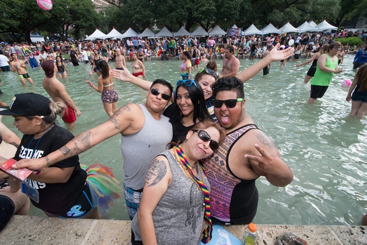 Festivalgoers enjoy a dip in City Hall's reflecting pool during Pride Houston 2016. - PHOTO BY JACK GORMAN