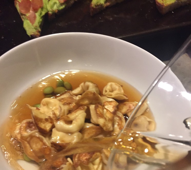 Compound stock consommé, tortellini in the style of potstickers, edamame. - PHOTO BY NICHOLAS L. HALL
