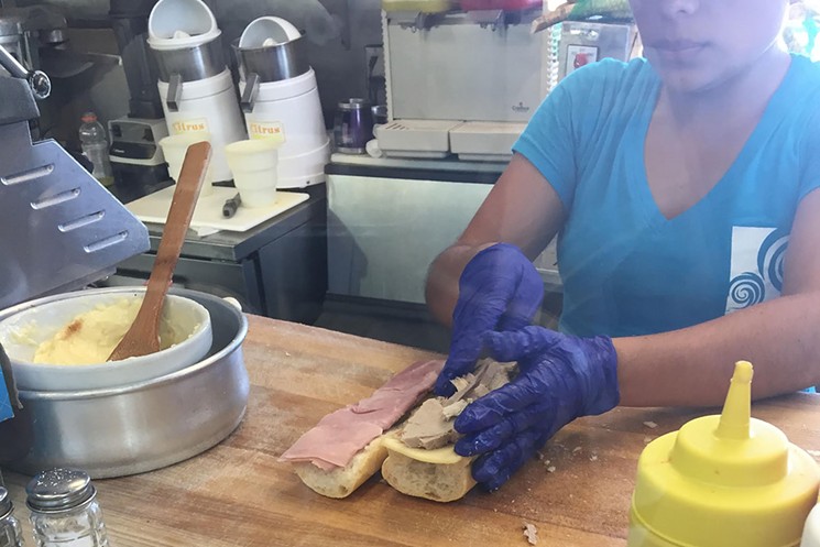 Roast pork and ham on a baguette being prepared at Las Ola's Cafe in Miami. - PHOTO BY JEFF BALKE