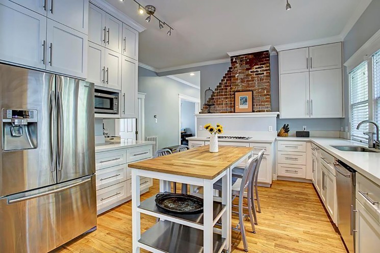 The kitchen at 811 Highland has shaker cabinets and an exposed brick accent wall. - PHOTO BY TK IMAGES