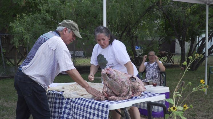 Adán Medrano and Christine Ortega prep the “cabeza de pozo,” a cow’s head that will cook in a backyard hole-in-the-ground earth oven overnight. - PHOTO BY  VIRGINIA DIAZ-LAUGHLIN