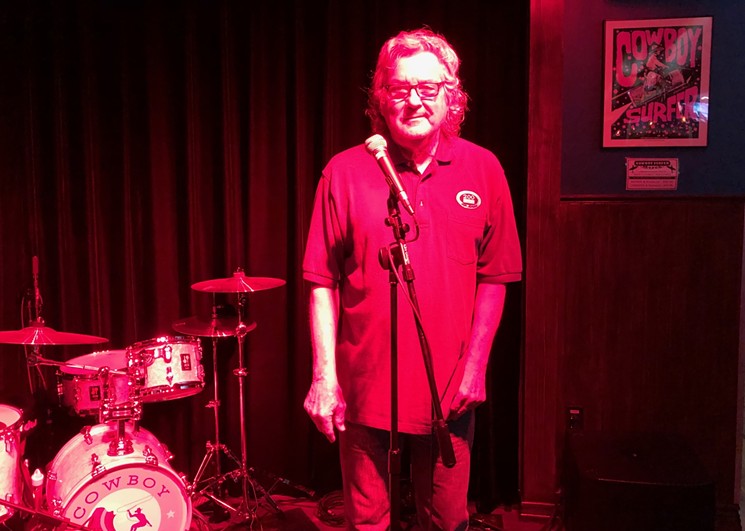 Jim Jard onstage at the Cowboy Surfer Bar. At the right is the new specially-designed poster by local artist Carlos Hernandez. - PHOTO BY BOB RUGGIERO