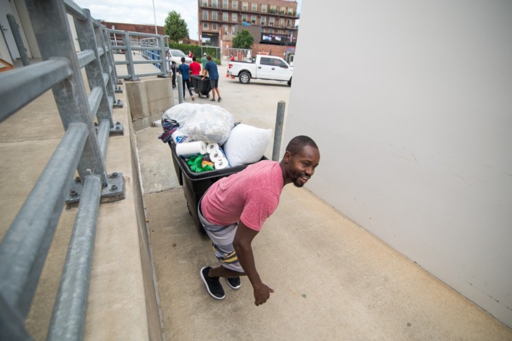 A volunteer transports donations for Harvey relief at BBVA Compass Stadium. - PHOTO BY JACK GORMAN