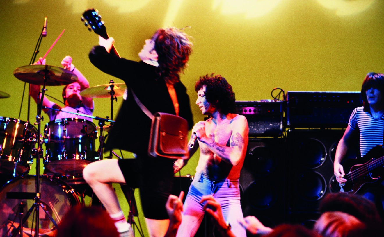 AC/DC's Phil Rudd, Angus Young, Bon Scott, and Cliff Williams in flight onstage.